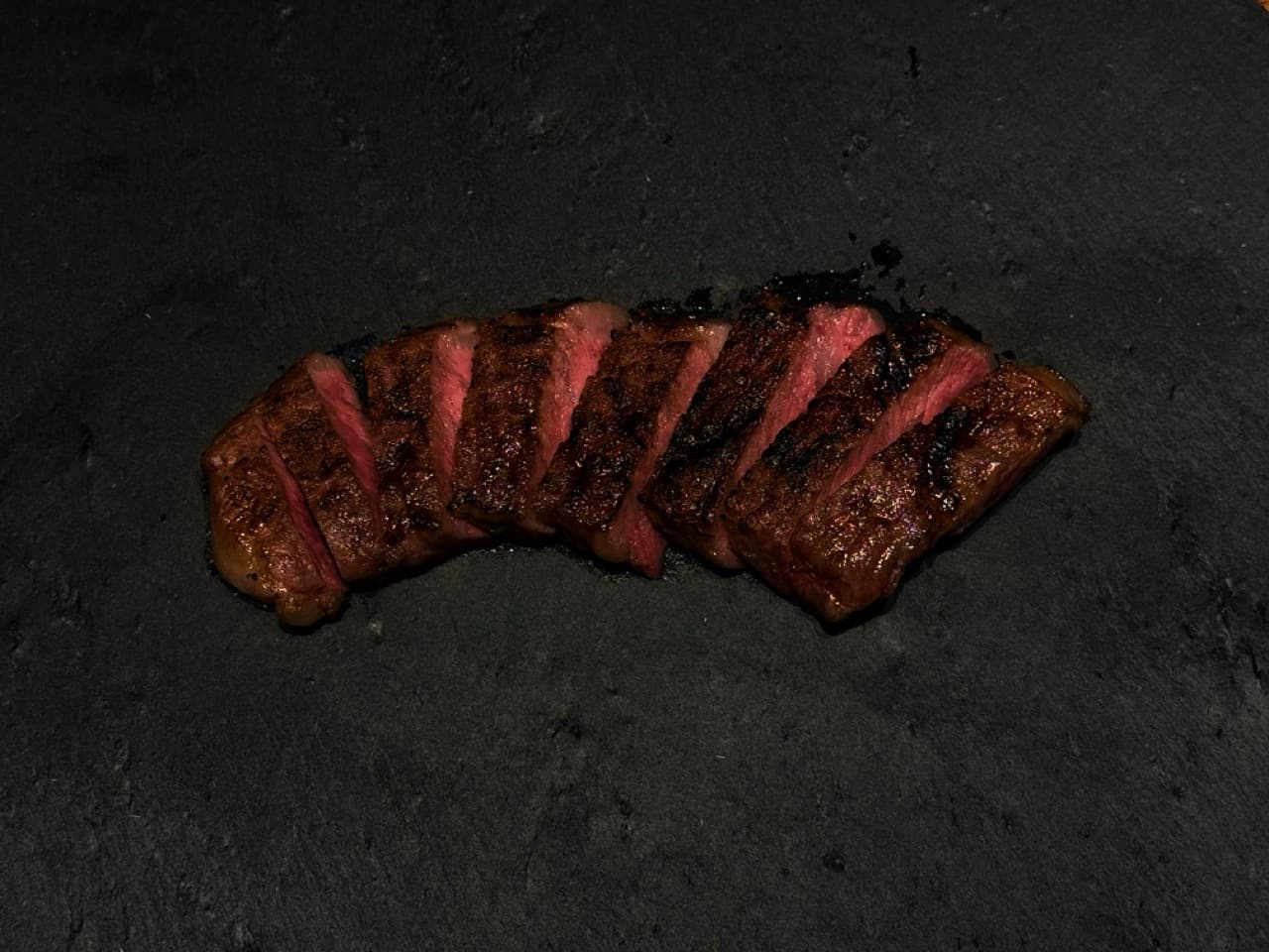 Sliced medium-rare Japanese Wagyu steak on a dark slate plate